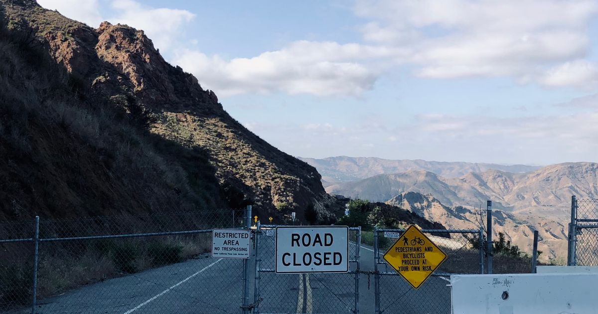 Ein geschlossenes Tor sperrt eine Bergstraße, Schild Road Closed